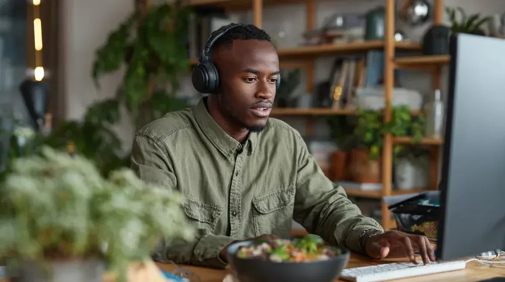 Un professionnel avec casque d’écoute suit une formation en ligne à son poste